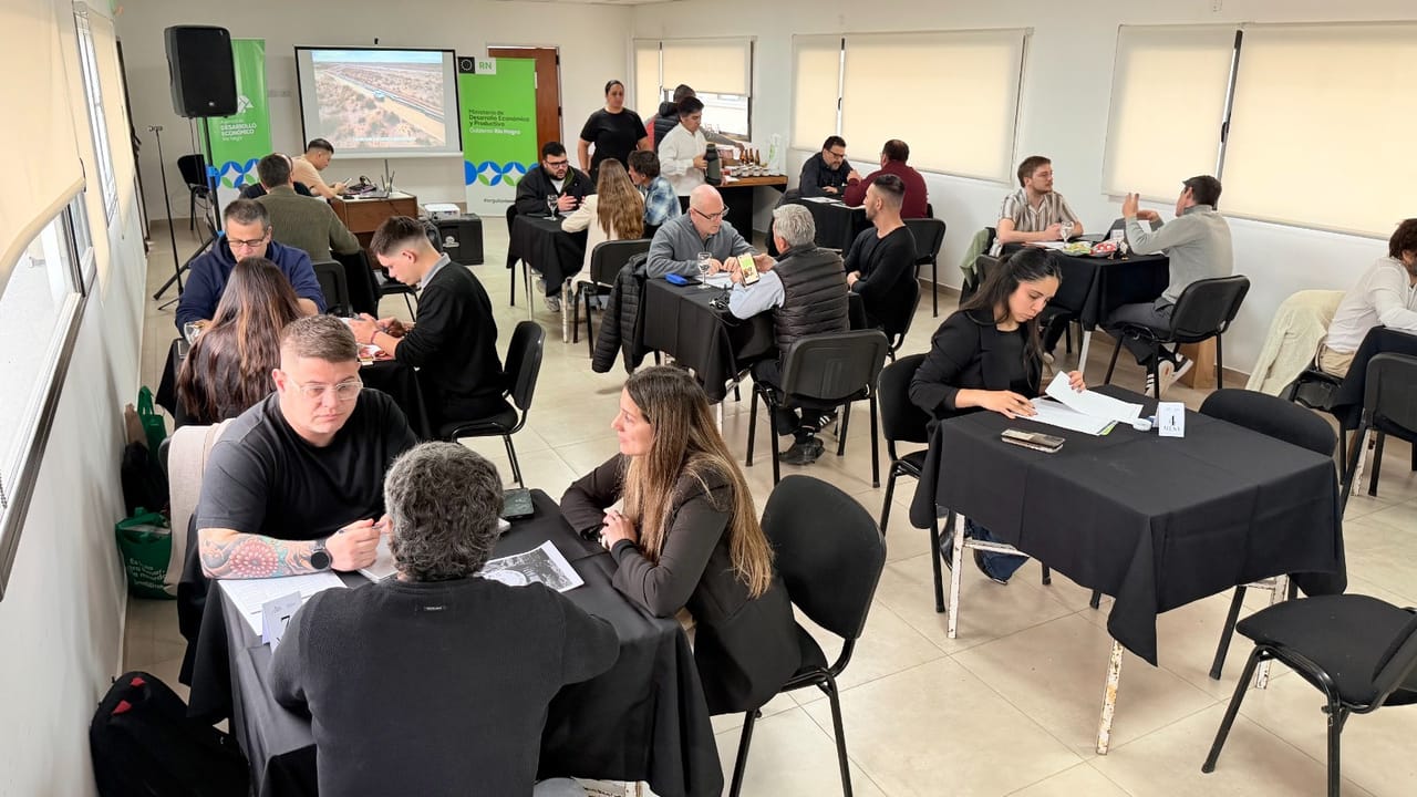 Productores de Río Negro mostrando frutas y verduras mientras visitantes inspeccionan la infraestructura tecnológica de la plantación.